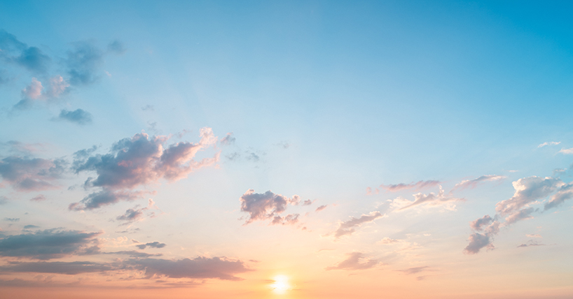 Sun rises in a bright blue sky with a few whispy clouds